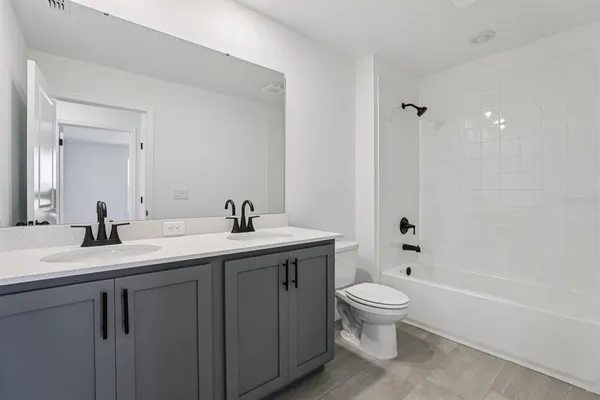 a bathroom with a granite countertop sink a toilet and a tub