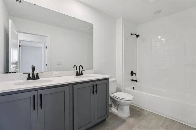 a bathroom with a granite countertop sink a toilet and a tub