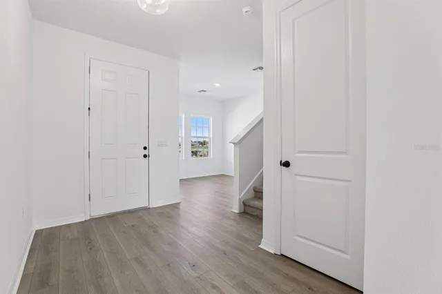 an empty room with wooden floor and a hallway