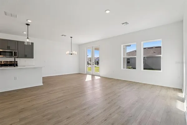 a view of empty room with wooden floor and kitchen view