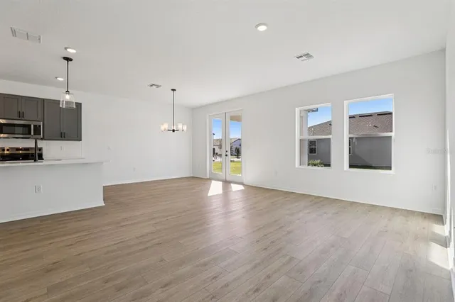 a view of empty room with wooden floor and kitchen view
