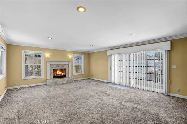 an empty room with windows and fireplace