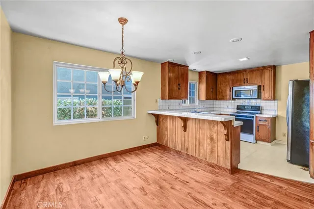 a kitchen with stainless steel appliances granite countertop a stove a sink dishwasher a refrigerator and microwave with wooden floor