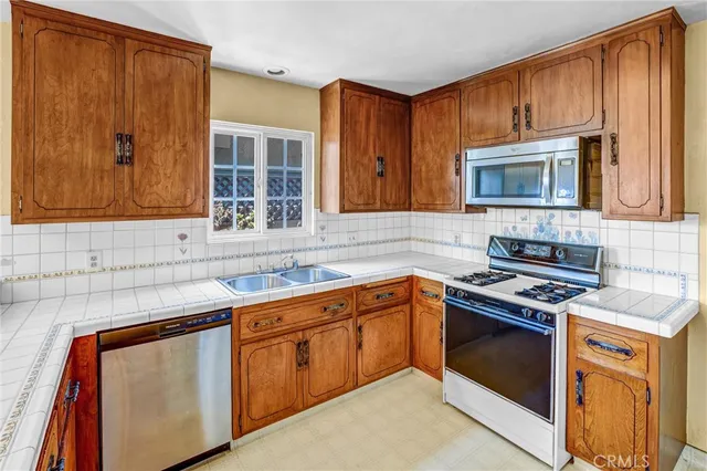 a kitchen with stainless steel appliances granite countertop wooden cabinets stove top oven and sink
