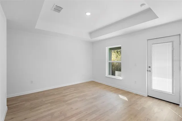 an empty room with wooden floor and windows
