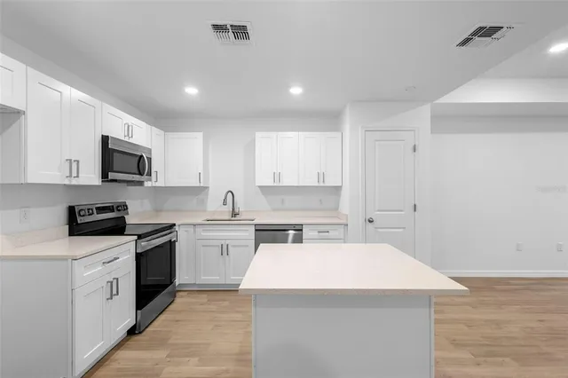 a kitchen with a sink a stove top oven and white stainless steel appliances