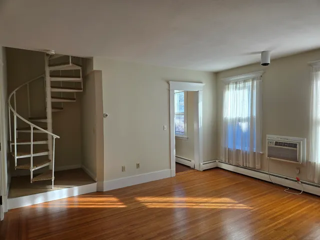 an empty room with wooden floor closet and windows