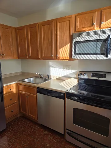 a kitchen with granite countertop wood cabinets stainless steel appliances and a sink