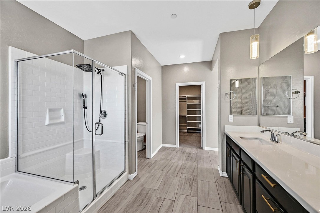 1106 Langston Ranch Avenue Henderson, NV 89002 - Photo 20 of 36 A well-appointed primary bathroom showcases a glass-enclosed shower, a double vanity, and wood-look tile flooring.