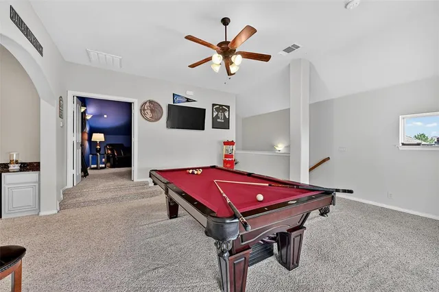 a room with pool table and ceiling fan