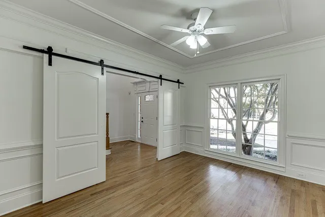 an empty room with wooden floor fan and windows