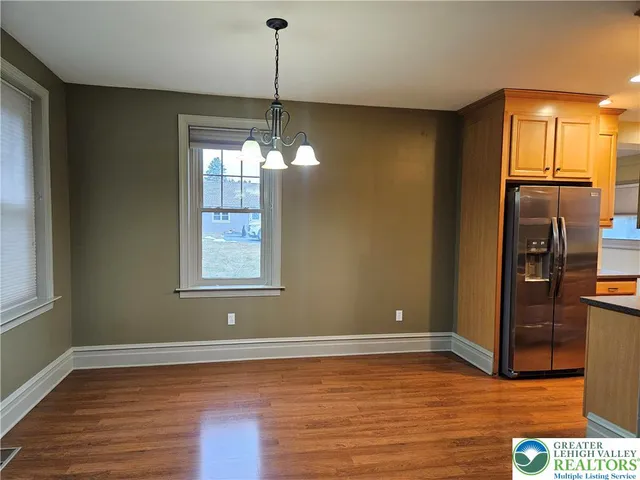 a view of an empty room with wooden floor and windows