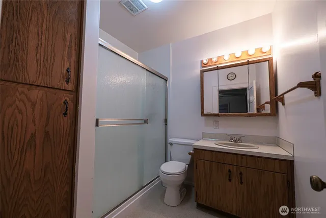 a bathroom with a toilet sink vanity granite and mirror