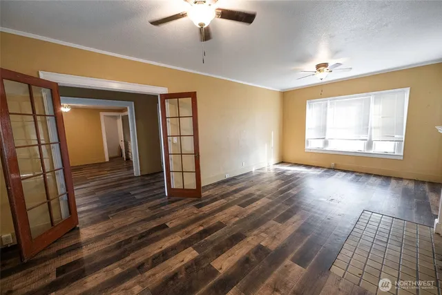 an empty room with wooden floor chandelier and windows