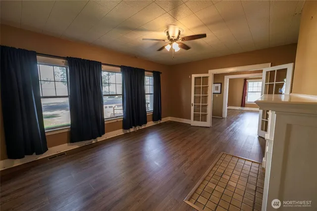 a view of an empty room with wooden floor and a window