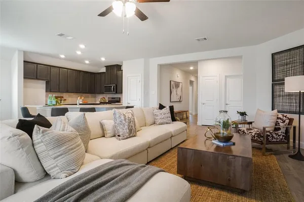 a living room with furniture kitchen view and a chandelier