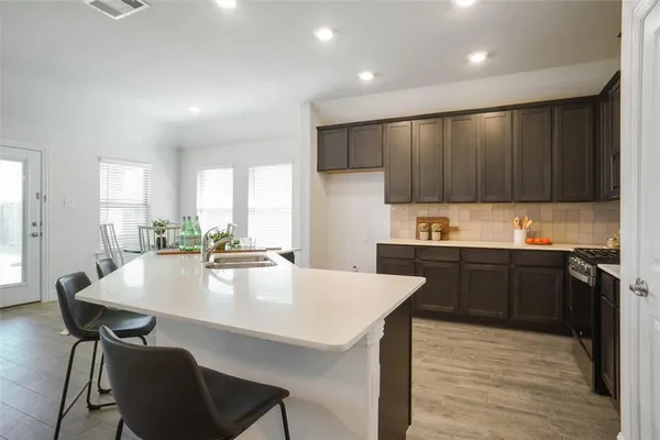 a large kitchen with kitchen island a stove a table and chairs in it