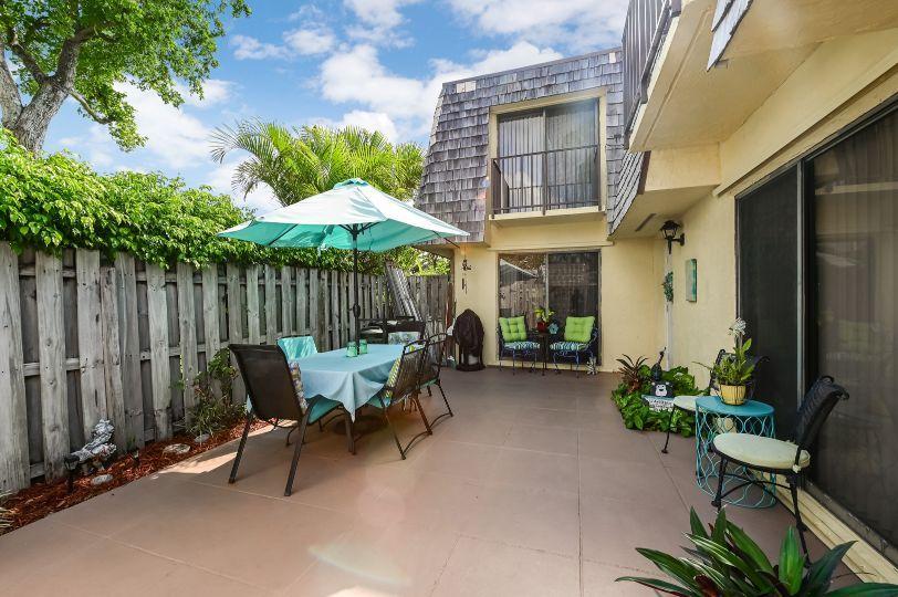 126 Woodland Road Palm Springs, FL 33461 - Photo 17 of 19 a view of a patio with a table and chairs under an umbrella