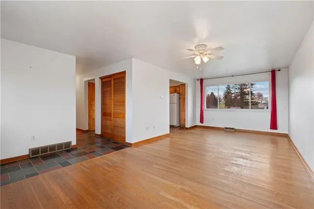 a view of an empty room with a window and a kitchen