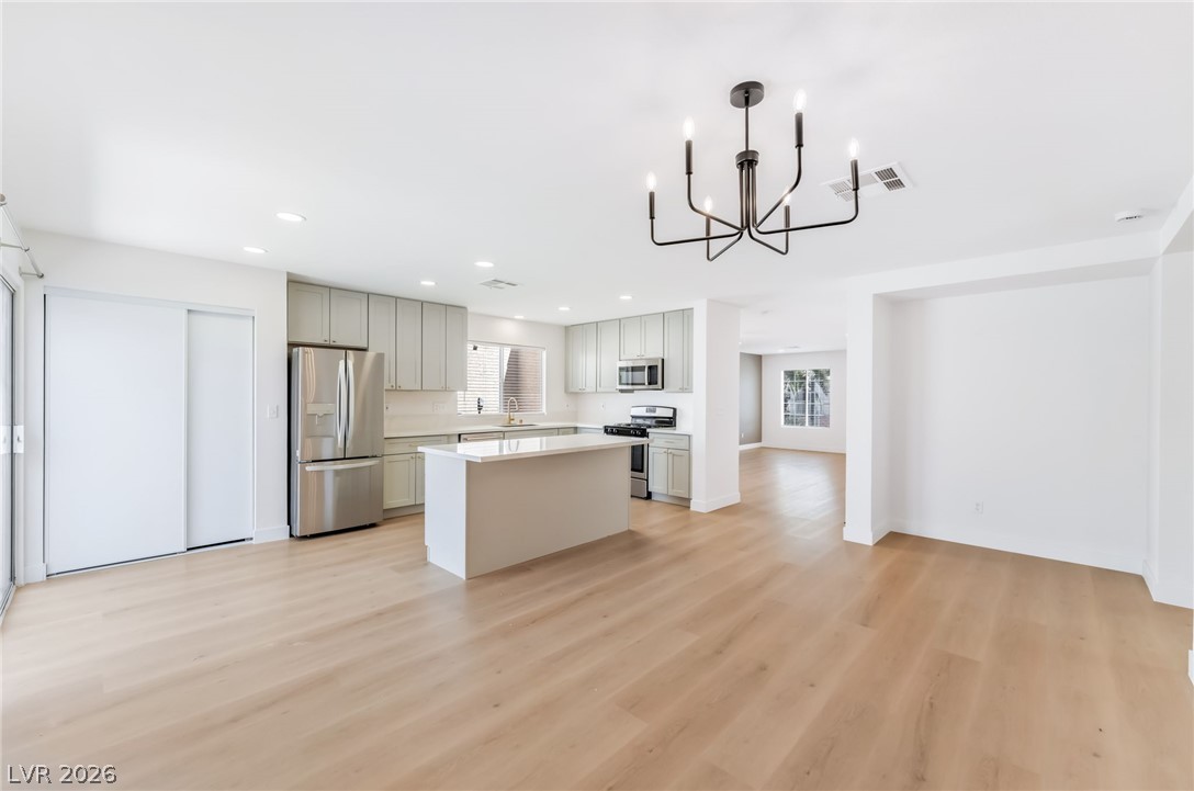 668 Rising Brook Drive Henderson, NV 89011 - Photo 6 of 22 A streamlined open concept kitchen and living area, featuring light hardwood flooring and modern fixtures.