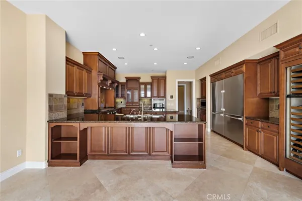 a kitchen with stainless steel appliances granite countertop a refrigerator a stove and a sink