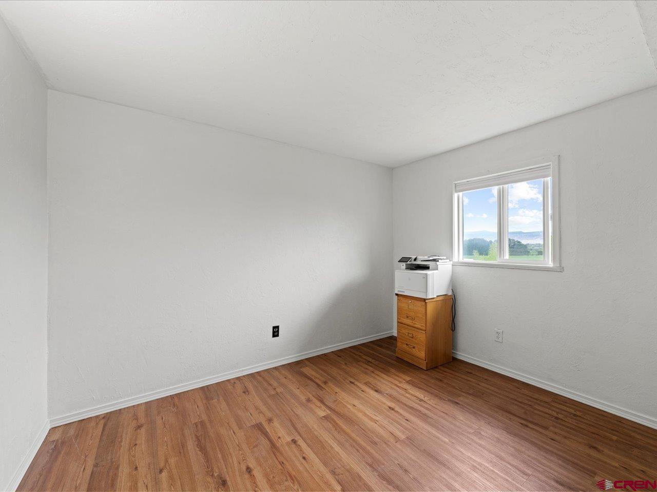 6910 High Mesa Road Olathe, CO 81425 - Photo 24 of 40 an empty room with wooden floor and windows