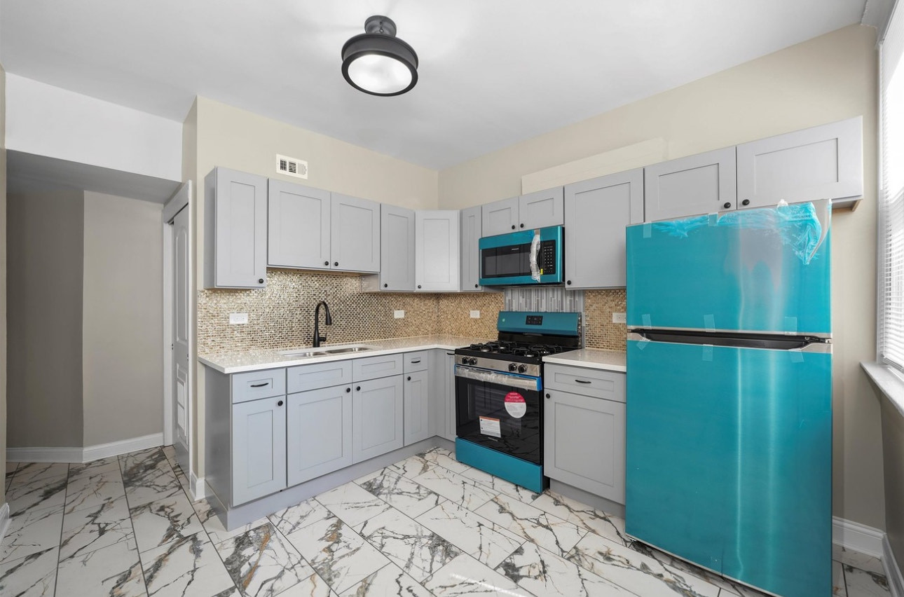 7548 South Harvard Avenue, Unit 2 Chicago, IL 60620 - Photo 3 of 7 a kitchen with a refrigerator sink and white cabinets