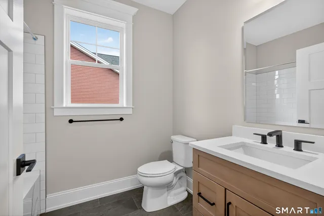 a bathroom with a granite countertop toilet sink and mirror