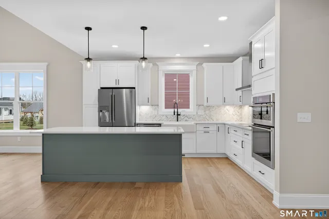 a kitchen with stainless steel appliances a kitchen island hardwood floor sink stove and wooden cabinets