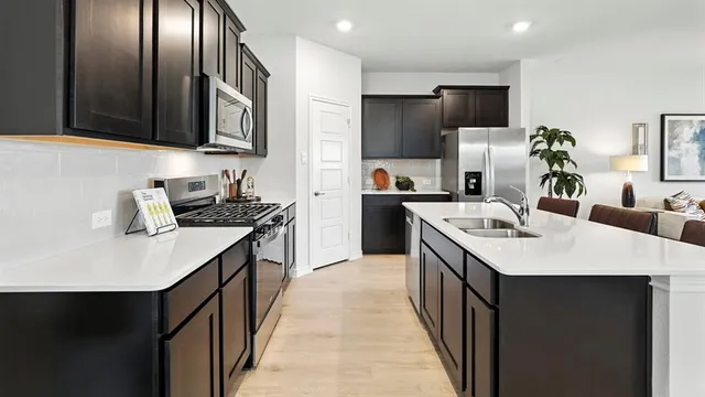 a kitchen with stainless steel appliances a sink stove refrigerator and cabinets