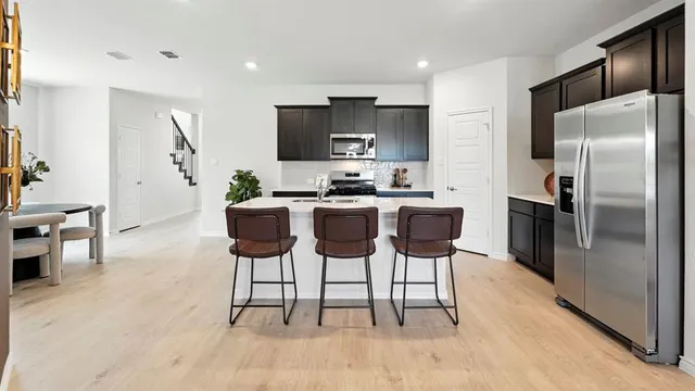 a kitchen with stainless steel appliances a table chairs refrigerator and a sink