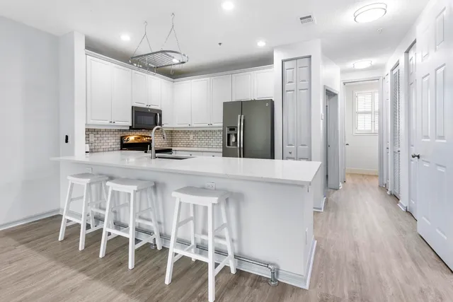 a kitchen with stainless steel appliances a dining table chairs refrigerator and microwave