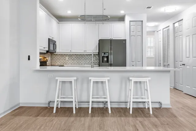 a kitchen with stainless steel appliances kitchen island granite countertop a table chairs sink and cabinets