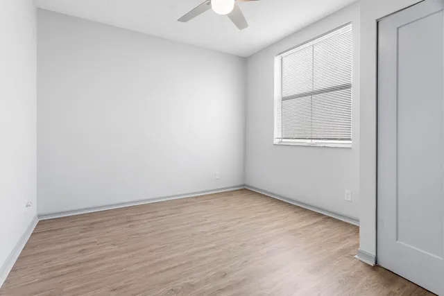 an empty room with a window and a ceiling fan