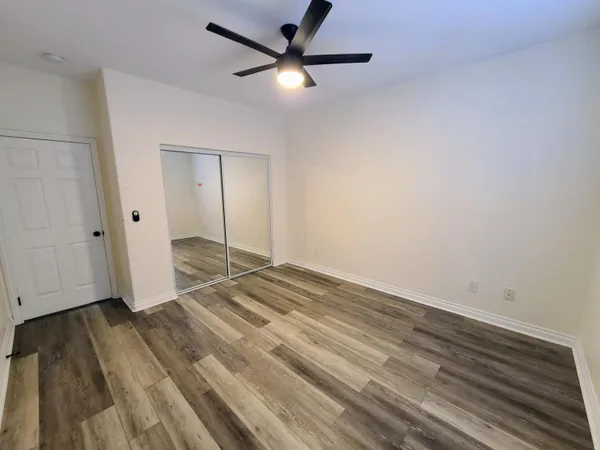 an empty room with wooden floor a ceiling fan and stairs