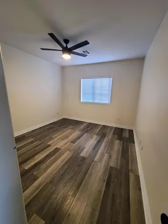 an empty room with wooden floor and a ceiling fan