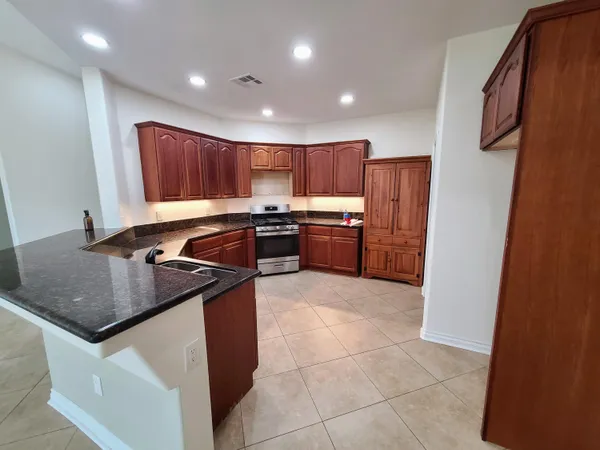 a kitchen with kitchen island granite countertop a sink stove and refrigerator