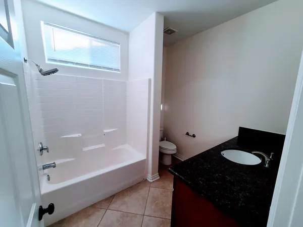 a bathroom with a granite countertop sink and a bathtub