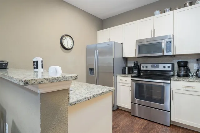 a kitchen with stainless steel appliances granite countertop a stove a refrigerator and a microwave