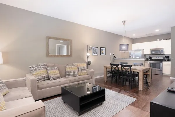 a living room with furniture a wooden floor and kitchen view