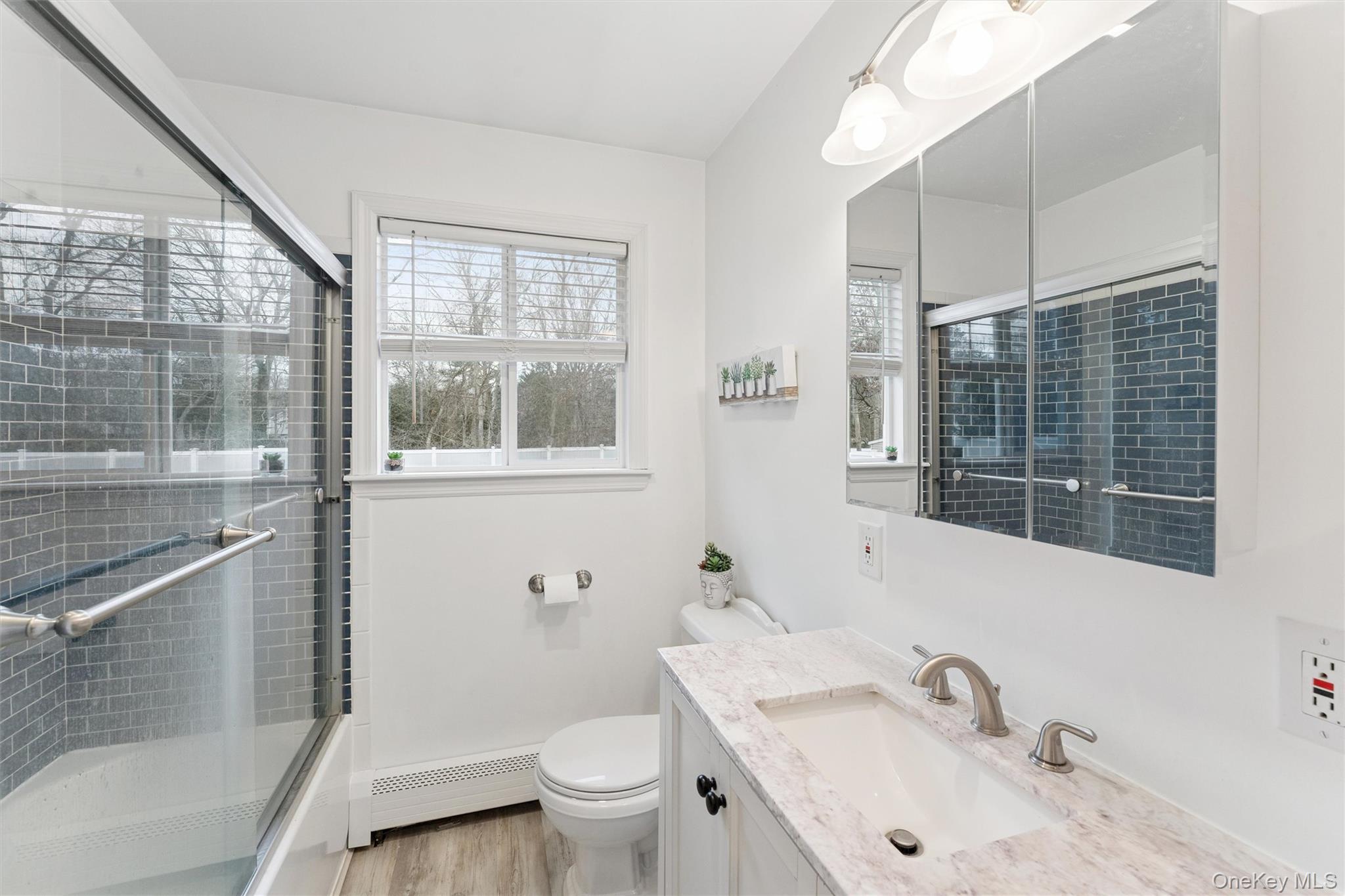 31 Howell Place Speonk, NY 11972 - Photo 14 of 16 Full bath featuring baseboard heating, vanity, combined bath / shower with glass door, and light wood-type flooring