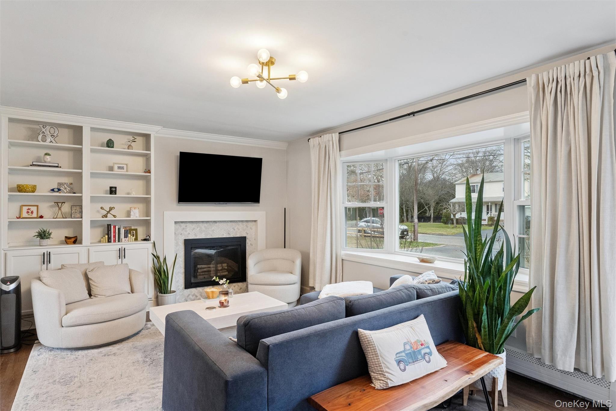 31 Howell Place Speonk, NY 11972 - Photo 8 of 16 Living room with a premium fireplace, wood finished floors, a chandelier, a baseboard heating unit, and built in features