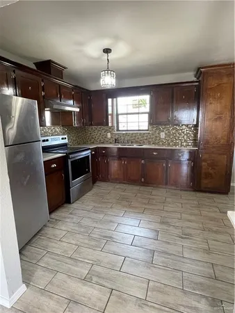 a large kitchen with granite countertop a stove a sink and a refrigerator