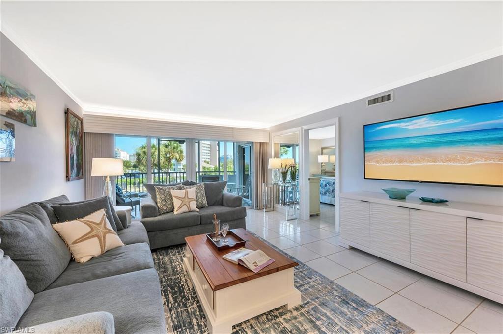 12945 Vanderbilt Drive, Unit 304 Naples, FL 34110 - Photo 16 of 45 a living room with furniture and a flat screen tv
