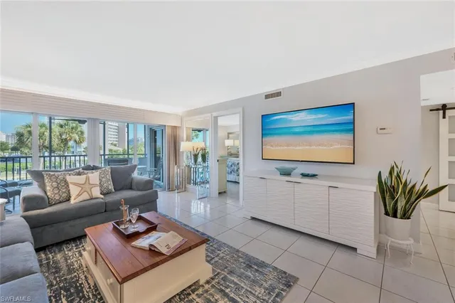 a living room with furniture flat screen tv and a floor to ceiling window