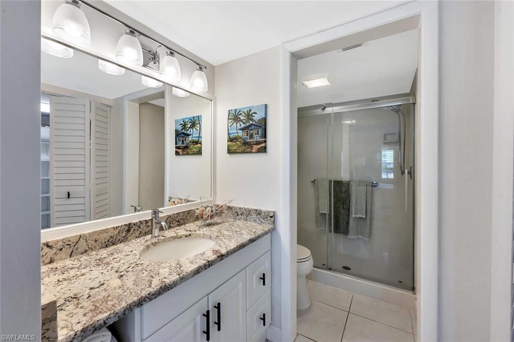 12945 Vanderbilt Drive, Unit 304 Naples, FL 34110 - Photo 26 of 45 a bathroom with a granite countertop sink and a mirror