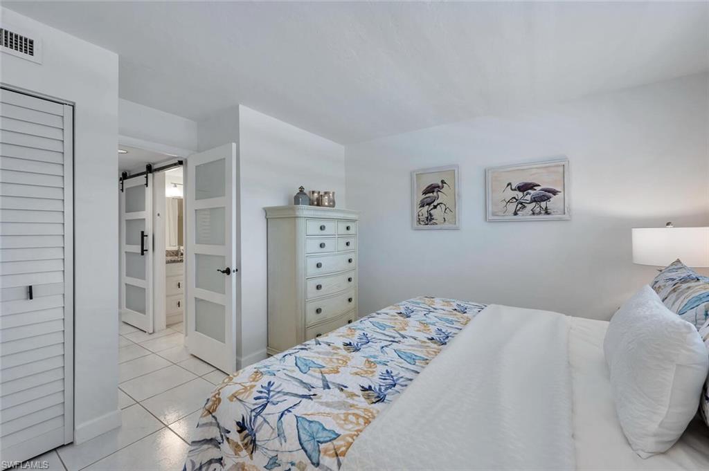 12945 Vanderbilt Drive, Unit 304 Naples, FL 34110 - Photo 29 of 45 a bedroom with a bed and a view of bathroom