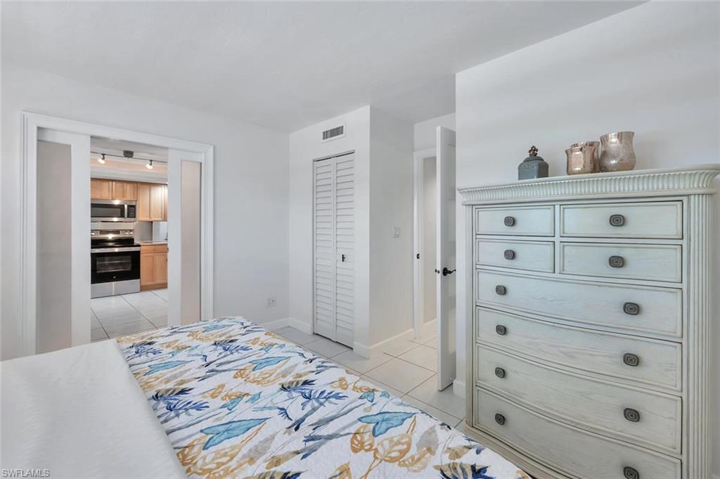 12945 Vanderbilt Drive, Unit 304 Naples, FL 34110 - Photo 30 of 45 a bedroom with a bed and a dresser