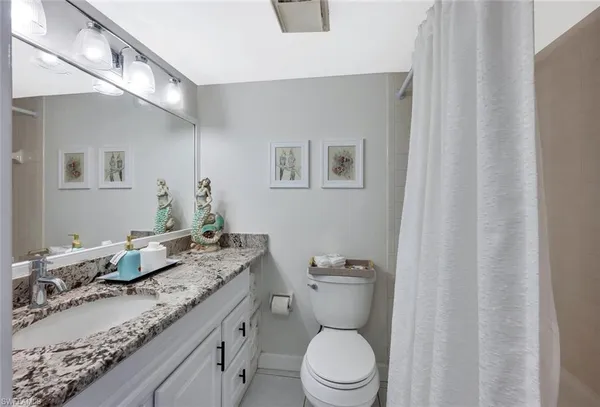 a bathroom with a granite countertop sink mirror vanity and toilet