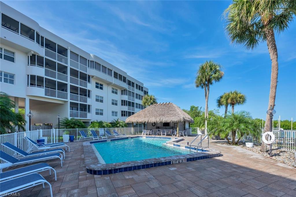 12945 Vanderbilt Drive, Unit 304 Naples, FL 34110 - Photo 34 of 45 a view of a patio with a table and chairs under an umbrella